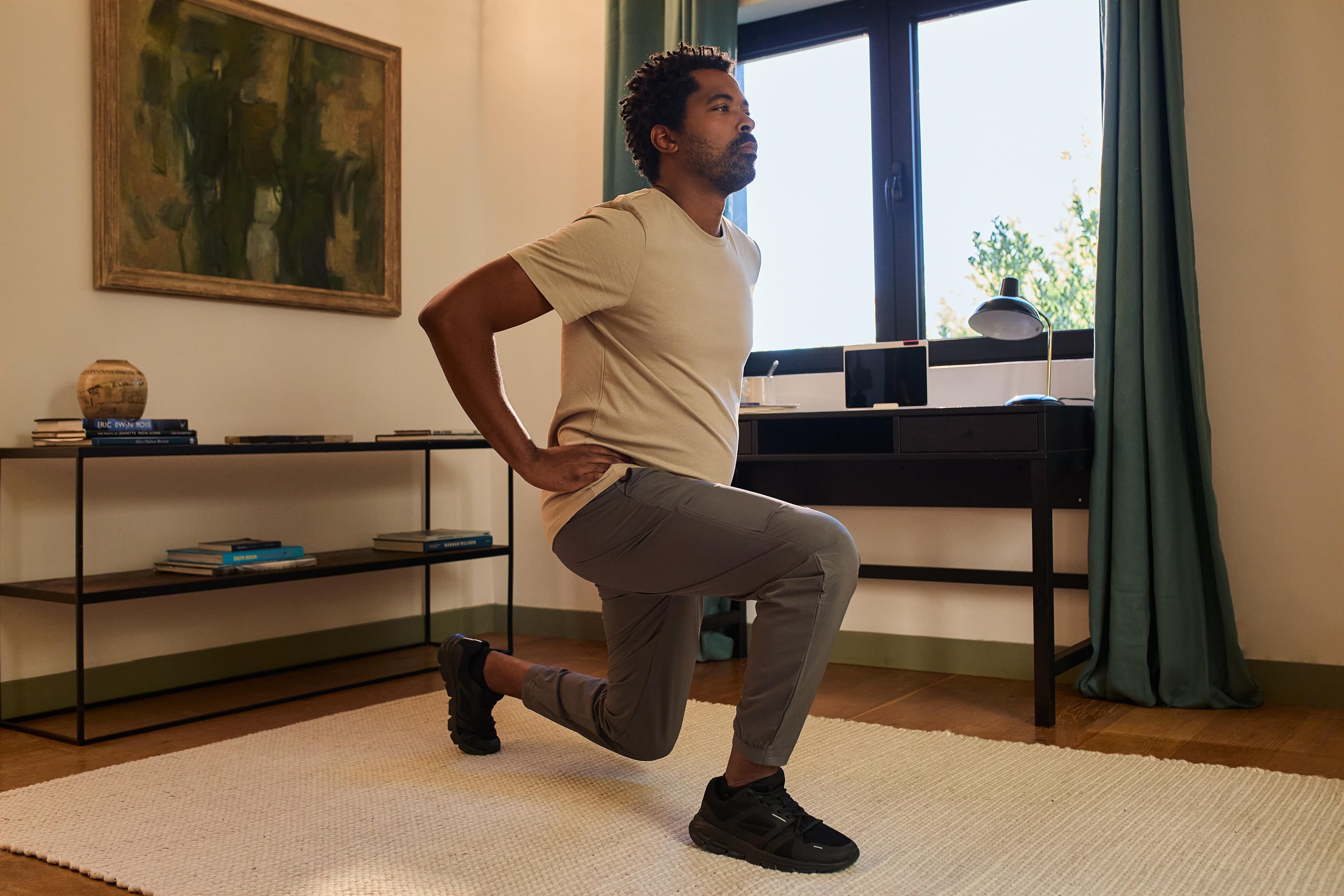 Man performing a lunge in his living room while looking ahead with confidence